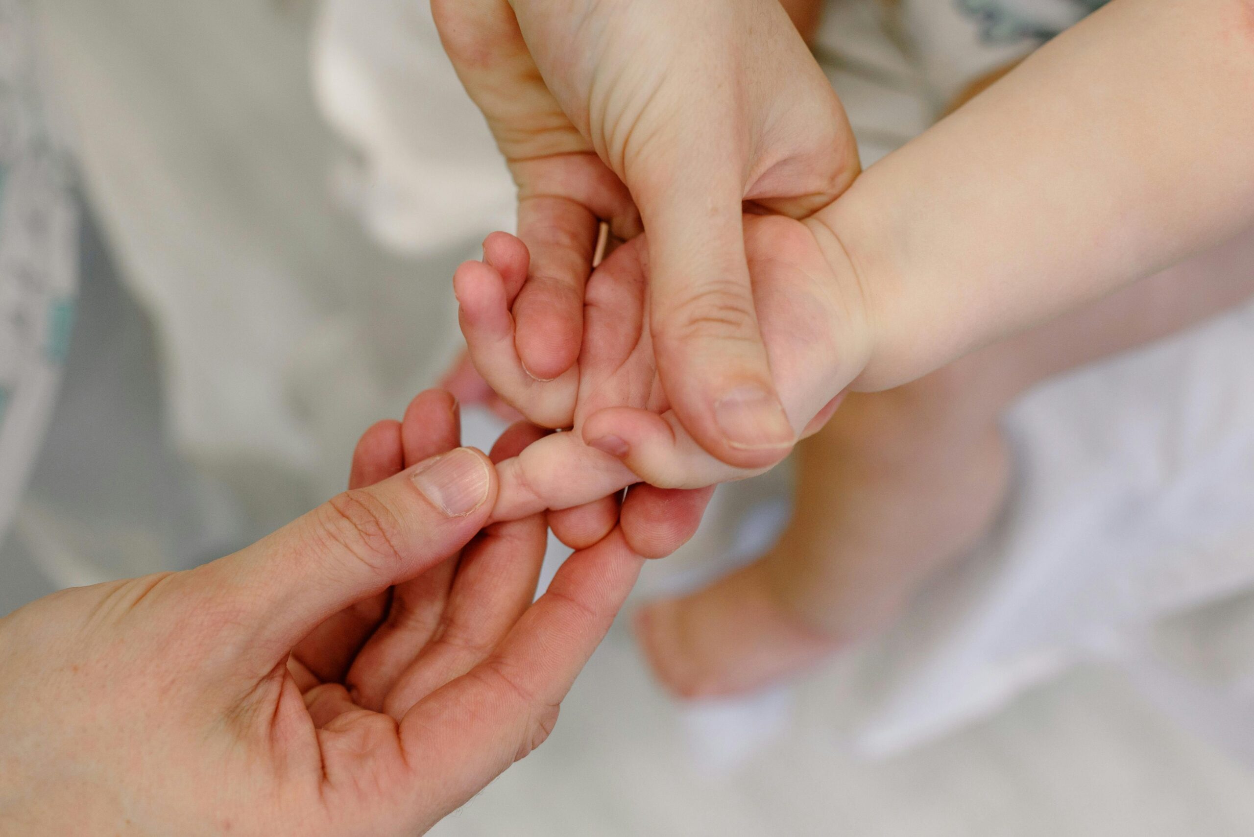 Close-up of an adult giving a gentle massage to a baby's hand, showcasing tender care and nurturing touch.
